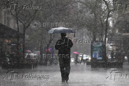 A man uses an umbrella to shelter from the rain as he walks along Pitt Street mall, Sydney