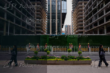 Workers walk past buildings under construction at Central Business District (CBD) in Beijing