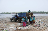 Contract workers clean a beach littered with garbage in Mumbai