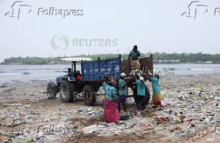 Contract workers clean a beach littered with garbage in Mumbai
