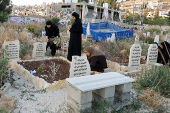 Palestinians visit the graves of their relatives at a cemetery in Jenin camp