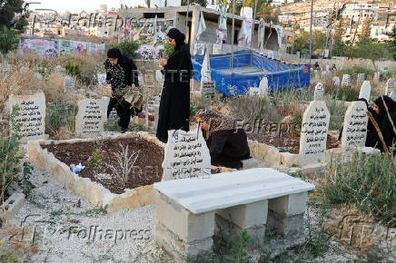 Palestinians visit the graves of their relatives at a cemetery in Jenin camp