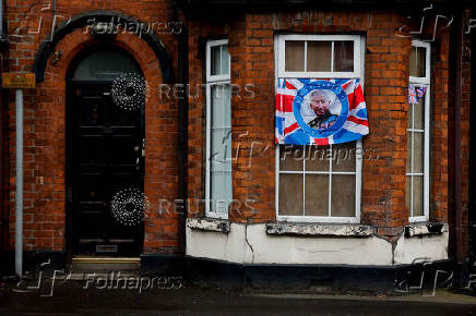A flag with a picture of Britain's King Charles hangs from a window, in Ballymena