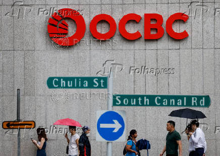FILE PHOTO: People pass an OCBC Bank signage in Singapore