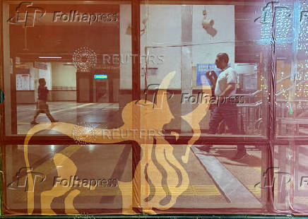 FILE PHOTO: A man walks past a logo of IndusInd Bank at a metro station in New Delhi
