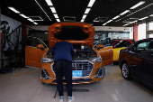 Person checks on an Audi car at a dealership inside a used car market in Beijing