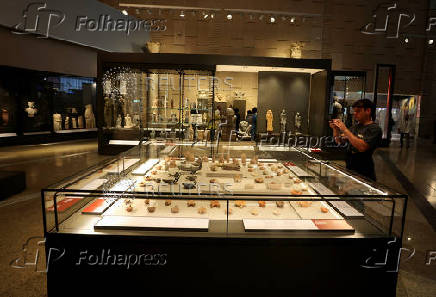 A visitor takes a photo of museum exhibits displayed at the Grand Egyptian Museum