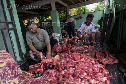 Volunteers cut freshly slaughtered beef to be distributed for free to the public during the sacrificial ritual celebrating Eid al-Adha, at a mosque in Banda Aceh