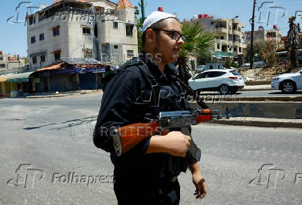 A man holds a weapon as he stands along a street, in Syria's predominantly Druze city of Sweida