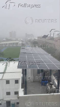 Strong gusts of wind blow away a solar panel on the roof of a building, as Typhoon Podul hits Taitung