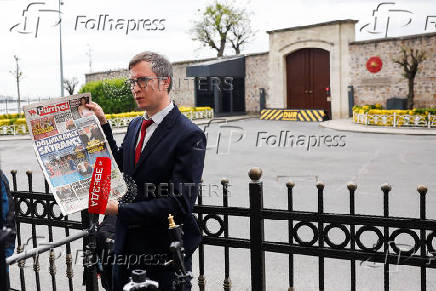 A Russian journalist holds up a newspaper outside the Turkish Presidency's Dolmabahce working office, in Istanbul