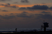 A swimmer heads into the ocean after sunset in California