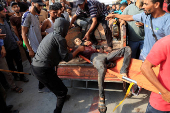 Palestinians carry a man who was wounded in an Israeli strike while waiting for aid, according to the Gaza Health Ministry, at Nasser hospital, in Khan Younis