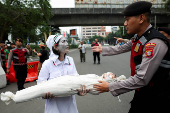 A police officer blocks an activist during a protest against Israel and in support of Palestinians in Gaza, outside the U.S. embassy in Jakarta