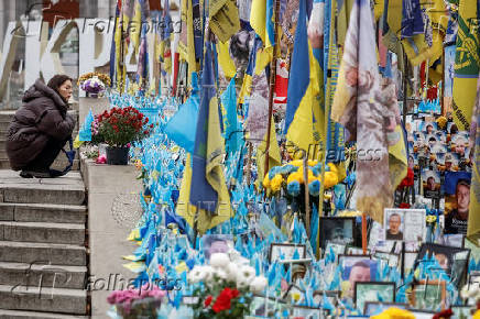 Woman sits in front of the makeshift memorial to fallen Ukrainian defenders at Independence Square in Kyiv