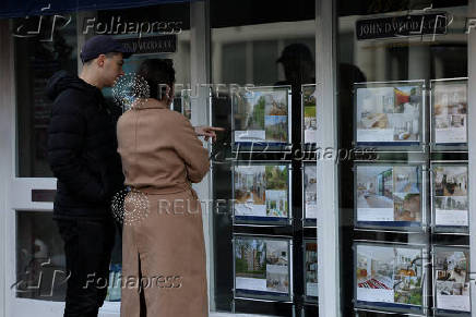 FILE PHOTO: People look at properties displayed in the window of a real estate agent's office in London