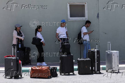 Expats, including diplomats from different nationalities, who were stranded in West Bank and Israel, wait as they hold belongings while being evacuated through the King Hussein Bridge crossing, in South Shuna