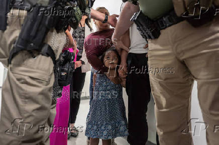 A child looks up at federal immigration officers as her father is detained at U.S. immigration court in Manhattan