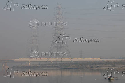 A man rows his boat in the Yamuna river on a smoggy morning