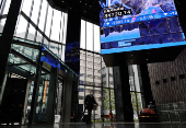 A man walks past an electronic board showing Nikkei share average in Tokyo