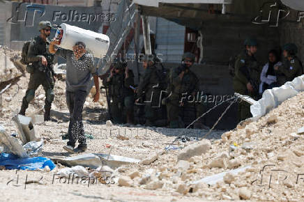Palestinians carry their belongings after Israel's decision to demolish their homes in Nur Shams camp