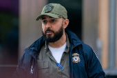 An ICE agent speaks to people lined up to enter the U.S. Immigration Court, in Manhattan