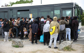 A group of migrants wait to board a coach organised by the authorities in Gravelines, France