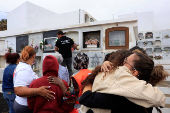 People stand with the mother of 12-year-old migrant girl Fatoumatta Banaro during her burial, after the wooden boat she was traveling on sank in the port of La Restinga
