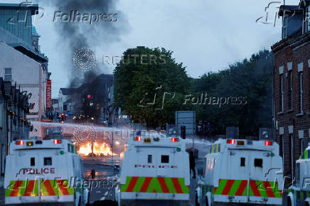 Armed police in riot gear stand guard during a second night of riots, in Ballymena