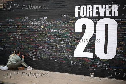 A fan adds a message to a memorial wall created near Anfield Stadium following the death of Liverpool soccer player Diogo Jota in Liverpool