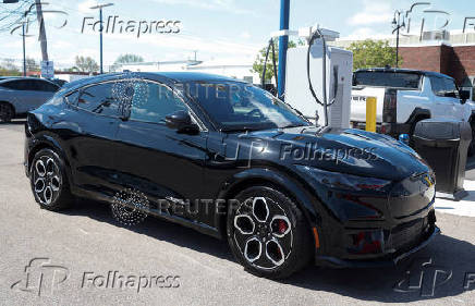 A 2025 Ford Mustang Mach_E sits at a charging station at a dealership in Dearborn, Michigan