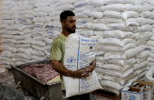 A Palestinian worker carries a sack of World Food Program (WFP) flour which is used to bake bread in a bakery that returned to operation after being closed due to a flour shortage, in Deir Al-Balah