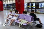 People rest on benches in an air-conditioned subway station amid a yellow alert for heat, in Shanghai