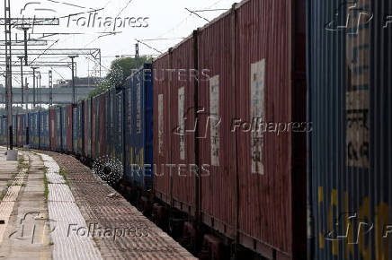 A goods train transporting containers moves near a railway station on the outskirts of Ahmedabad