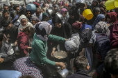 Displaced Palestinians collect donated food in Jabalia, northern Gaza