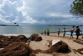 FILE PHOTO: Fishermen pull back a fishing net at a beach in Galle