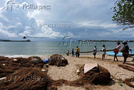 FILE PHOTO: Fishermen pull back a fishing net at a beach in Galle
