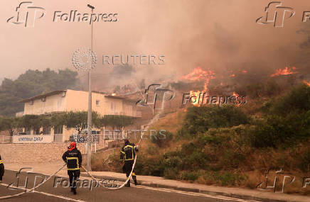 Firefighters try to extinguish the wildfire in Pisak