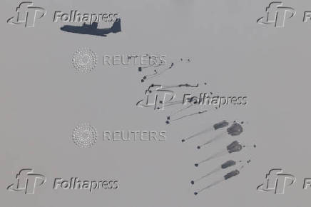 Aid packages dropped from an airplane descend over Gaza Strip, as seen from Israel