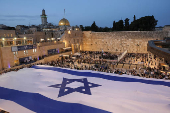 People hold a giant Israeli flag by the Western Wall, in Jerusalem's Old City