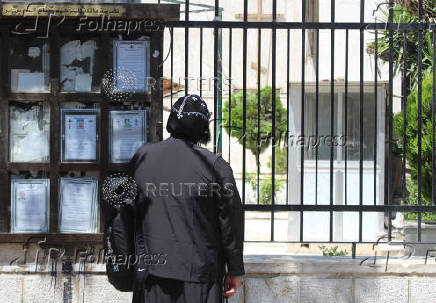 A person stands next to funeral notices at Mar Elias Church in Damascus