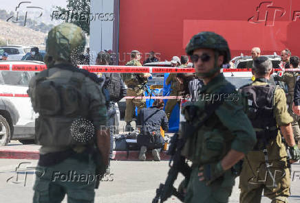 Israeli security personnel stand guard near the scene of a stabbing attack, in Gush Etzion
