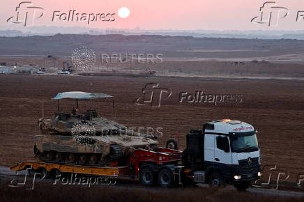 A truck carrying a tank drives on the Israeli side of the Israel-Gaza border