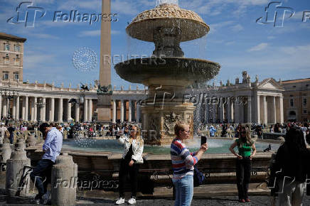 People take pictures with phones at St. Peter's Square in the Vatican