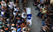 Mourners carry the body of a Palestinian journalist, Suleiman Hajjaj, who was killed in an Israeli airstrike, in Gaza City