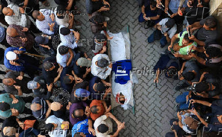 Mourners carry the body of a Palestinian journalist, Suleiman Hajjaj, who was killed in an Israeli airstrike, in Gaza City