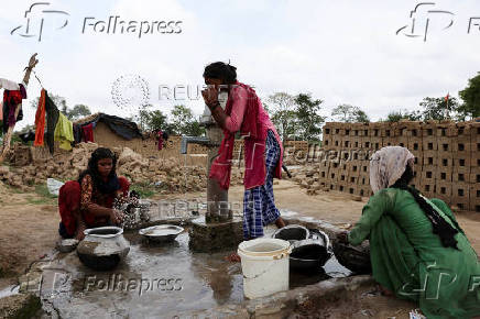 Women workers wash utensils using soil and water at a brick kiln, in Mathura