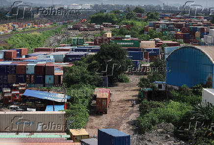 A man rides a bike past shipping containers at a warehouse in Navi Mumbai