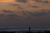 A swimmer heads into the ocean after sunset in California