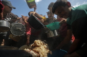 Displaced Palestinians collect donated food in Jabalia, northern Gaza